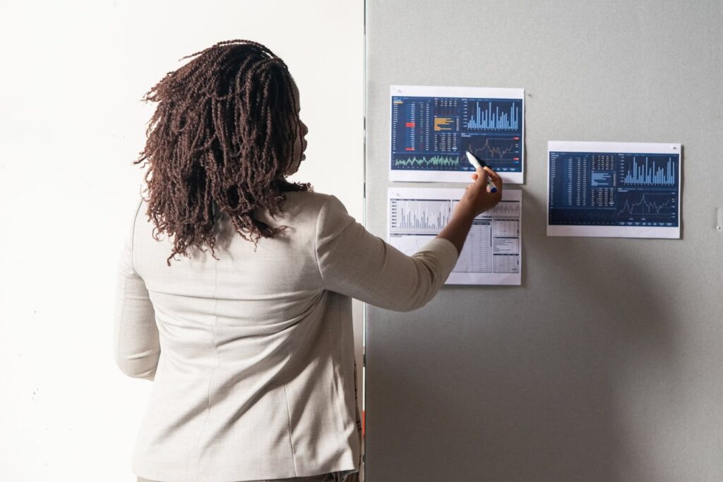 pexels-photo-6248946 A businesswoman in a suit presenting financial data on charts during a meeting.